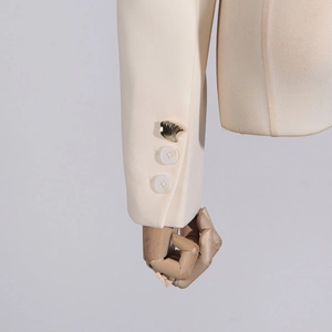 Detail of cream blazer sleeve with decorative gold shell button and white buttons