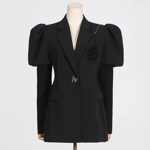 Dettaglio maniche a sbuffo e ricamo di paillettes nere su giacca blazer da donna