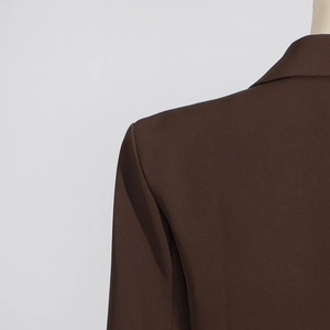 Détail de l'épaule d'un blazer marron montrant la texture du tissu et les coutures