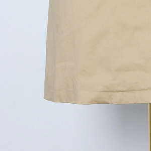 Close-up of khaki trench coat hem showing precise single-needle stitching and twill fabric
