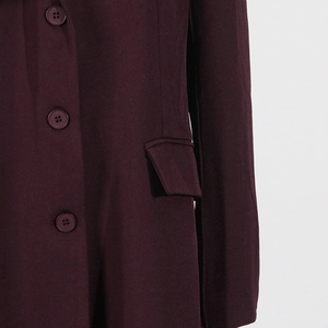 Detail of burgundy blazer showing resin buttons, flap pocket and smooth fabric texture