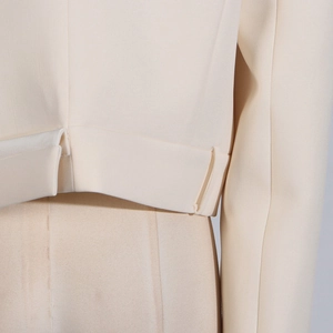 Detail shot of beige blazer hem featuring high-quality twill fabric and decorative strap