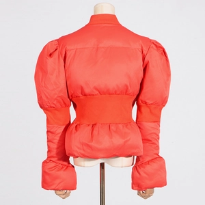 Détail de la veste orange vif à manches bouffantes avec taille côtelée et ourlet volanté