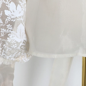 Detail of floral embroidery on sheer organza fabric with delicate rolled hem finishing