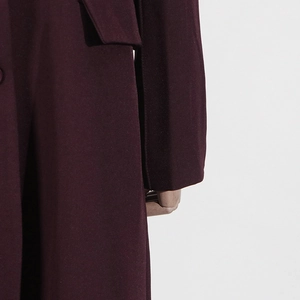 Close-up of deep wine red trench coat showing premium fabric texture and pocket flap detail