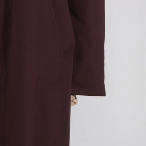 Detailed view of the side pocket and sleeve craftsmanship on a burgundy trench coat