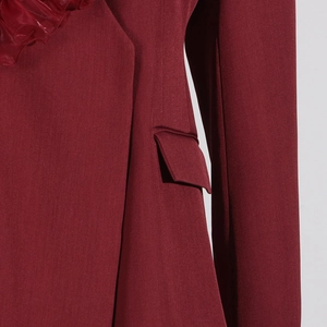Detailaufnahme des burgunderroten Blazers mit Rüschenkragen und Taschenklappen-Struktur