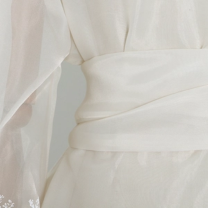 Detail of elegant white organza blouse showing pleated waist and lantern sleeve embroidery