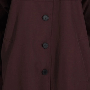 Close-up of three black buttons and stitch details on a burgundy trench coat front