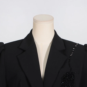 Dettaglio del blazer nero con eleganti nappe di paillettes e perline sul rever