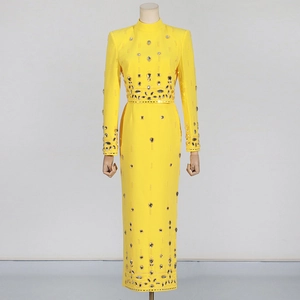 Détail d'une robe longue jaune à manches longues ornée de strass étincelants
