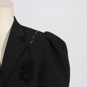 Dettaglio maniche a sbuffo e ricami di perline fatti a mano sul blazer nero