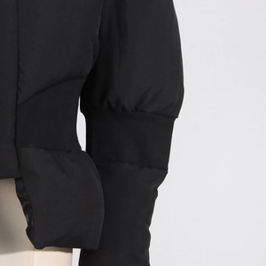 Détail de manches de veste noire avec poignets côtelés et élégants plis effet bouffant