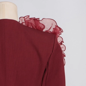 Makro-Detail der gerüschten Organza-Netznaht an burgunderroter Blazer-Schulter