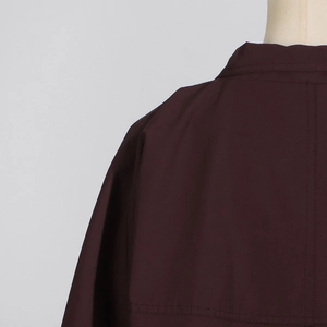 Detailed close-up of double-stitched seams on dark burgundy trench coat fabric