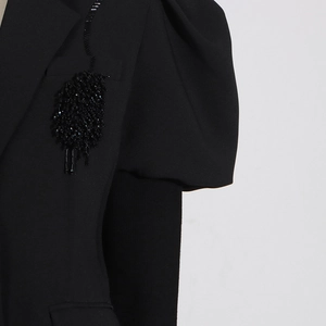 Dettaglio di blazer nero con maniche a sbuffo e ricami di perline fatti a mano pregiati