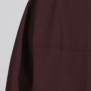 Detailed close-up showing stitching and texture of dark brown trench coat fabric
