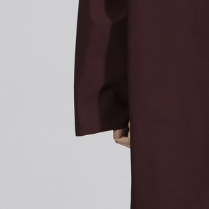 Detailed close-up of dark brown trench coat sleeve with smooth woven fabric texture