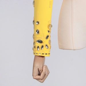 Détail de la manche jaune ornée de strass et d'une broderie de perles aux motifs floraux