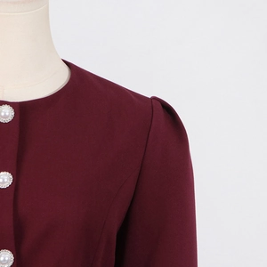 Close-up of wine red top featuring pearl buttons with gold trim and puff sleeve detail