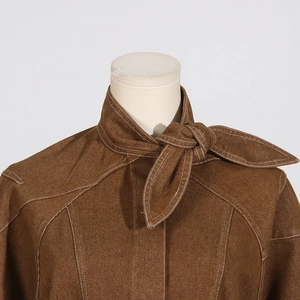 Close-up of brown textured shirt featuring white contrast stitching and tie-neck detail