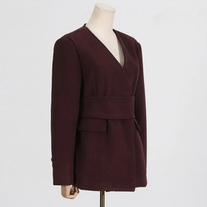 Detail of burgundy wool coat showing V-neck design, belt detail, and flap pockets