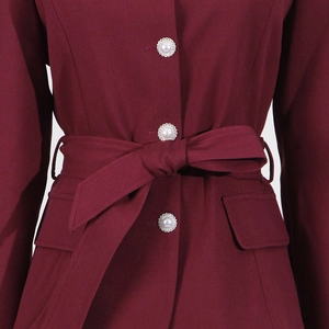 Detail of burgundy top with pearl buttons and a matching fabric bow belt waist