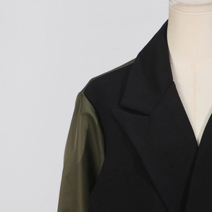 Detail view of British style coat with contrast olive green sleeve and notched lapel design