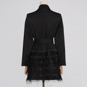 Dettaglio dell'abito blazer nero con perle bianche e frange in piume di struzzo