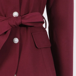 Detail of wine red twill jacket featuring pearl buttons with rhinestone trim and waist bow