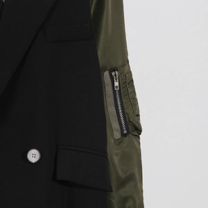 Detailed close-up of mixed-media trench coat with black fabric and olive utility sleeve