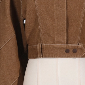 Close-up of brown jacket with white contrast stitching, waist loops and button details