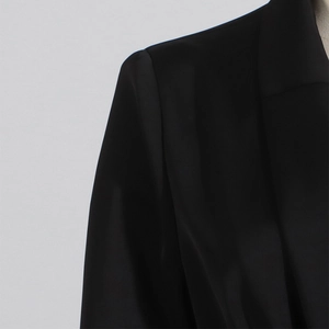 Dettaglio di un abito blazer in raso nero con spalle strutturate e finitura in seta opaca