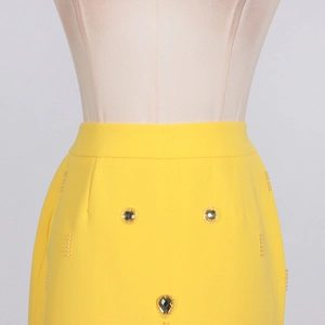 Détail d'une jupe jaune avec des perles verticales et des accents sertis de diamants