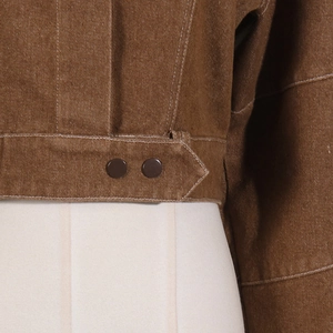 Detail of caramel brown denim waist with contrast stitching and double button closure