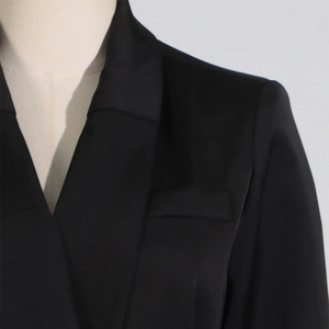 Dettaglio ravvicinato del revers del blazer in raso nero con bordo in piume di struzzo