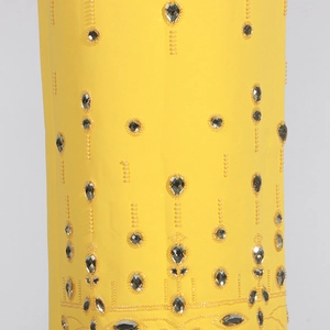 Détail du tissu jaune avec broderies complexes en strass argentés et perles fines