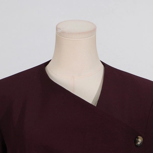 Close-up of asymmetrical collar and tortoise shell button on burgundy blazer