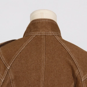 Detail view of brown twill outfit showing neck stitching and white contrast seams