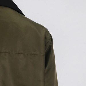 Detail shot of British-style trench coat back showing contrast black collar and olive fabric