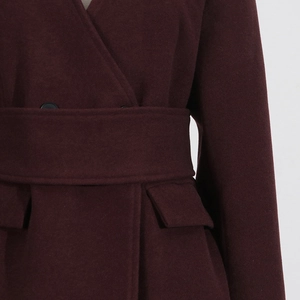 Close-up of burgundy wool jacket waist with thick belt, black buttons and flap pockets
