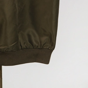 Detailed macro shot of deep olive green trench coat hem with elastic ribbed stitching