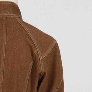 Detail of brown cotton jacket shoulder with white contrast stitching and thick texture