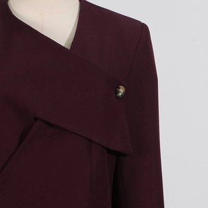 Detail of burgundy asymmetrical wrap top with a decorative marble button on the lapel