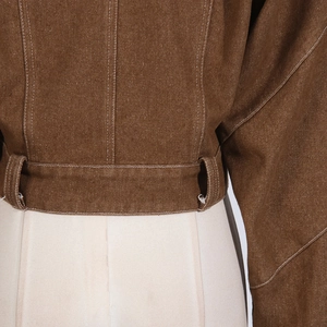 Close-up of brown twill jacket hem with white contrast stitching and belt loops