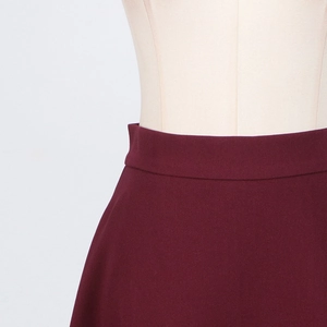 Detail of high-waist wine red skirt showing tight weave fabric on a mannequin