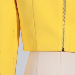 Détail de la veste jaune vif avec perles aux manches et fermeture éclair en métal
