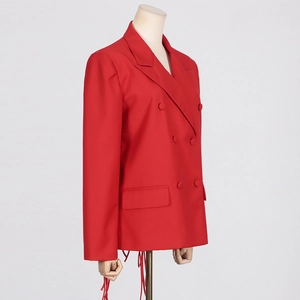 Detail of red double-breasted blazer featuring unique tassel fringe trim at the hemline