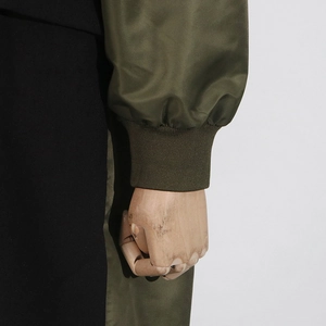 Detail of army green ribbed cuffs and glossy fabric of this paneled trench coat