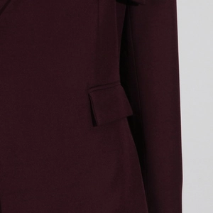 Detailed close-up of a burgundy suit jacket featuring a flap pocket and neat stitching